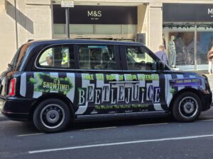 Taxi londonien arborant sur sa carrosserie une publicité pour beetlejuice