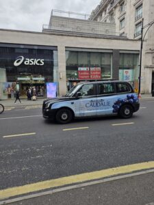 Taxi londonien arborant sur sa carrosserie une publicité pour caudalie