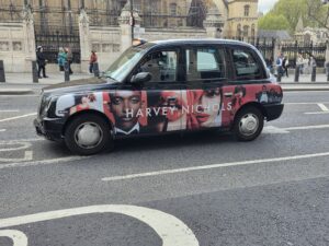 Taxi londonien arborant sur sa carrosserie une publicité pour harvey nochols