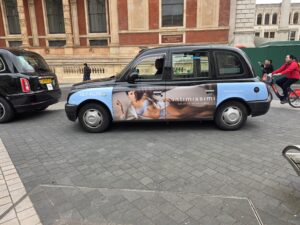 Taxi londonien arborant sur sa carrosserie une publicité pour intimissimi