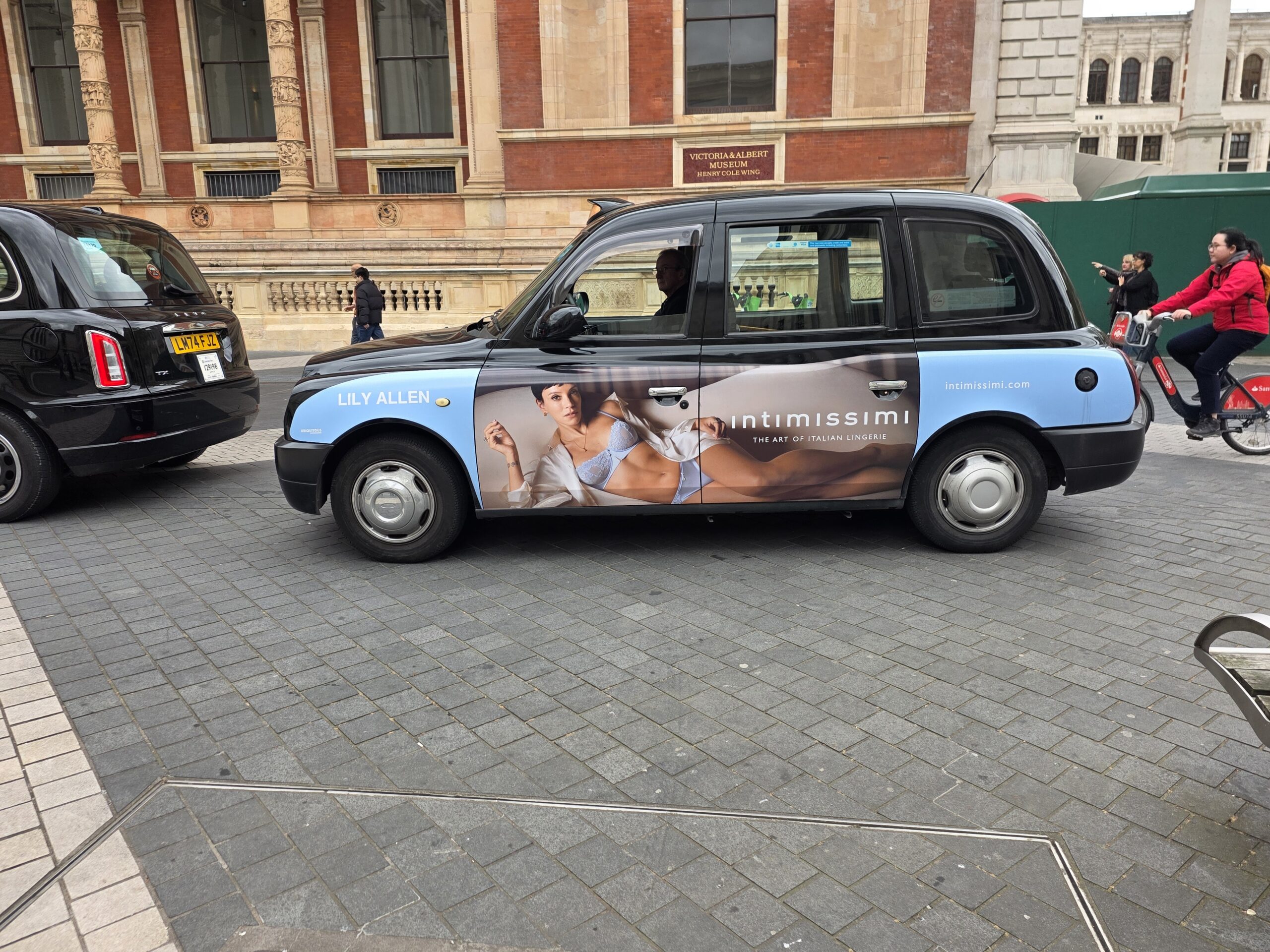 Taxi londonien arborant sur sa carrosserie une publicité pour intimissimi
