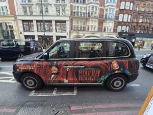 Taxi londonien arborant sur sa carrosserie une publicité pour moulin rouge