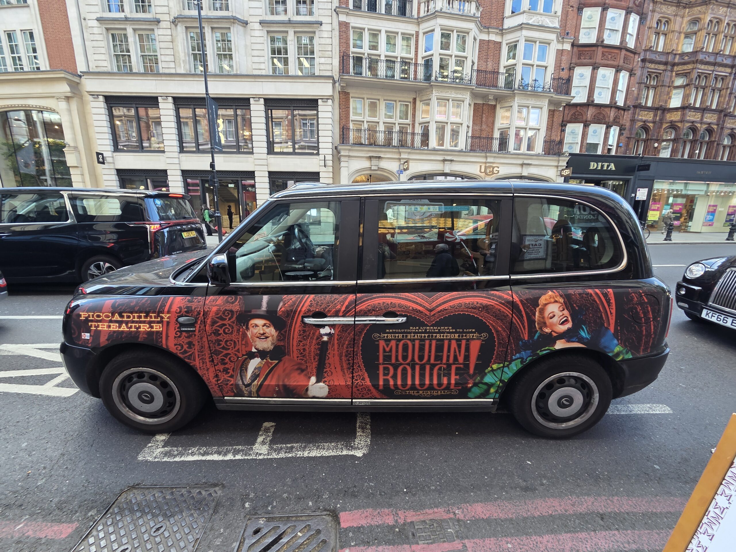 Taxi londonien arborant sur sa carrosserie une publicité pour moulin rouge