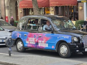 Taxi londonien arborant sur sa carrosserie une publicité pour taste that makes